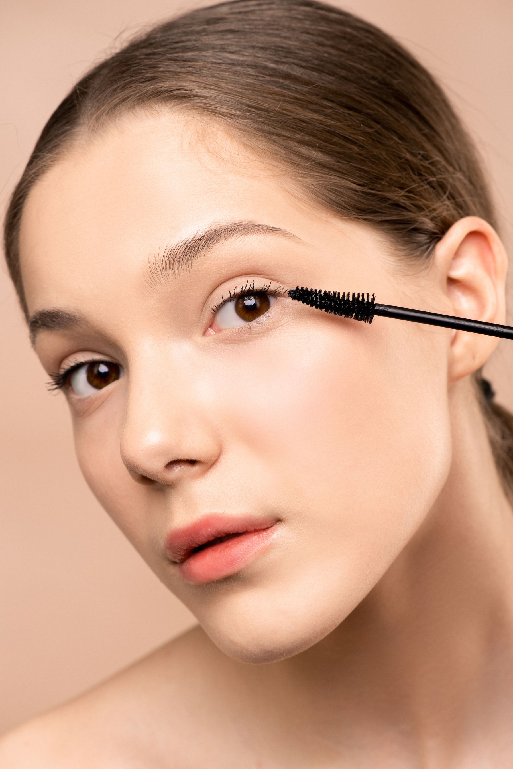 Woman applying mascara with a wand near her eyelashes